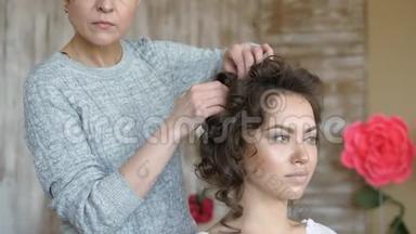 化妆师和模特一起工作。 理发师做模特的发型。 发夹抓住发卷
